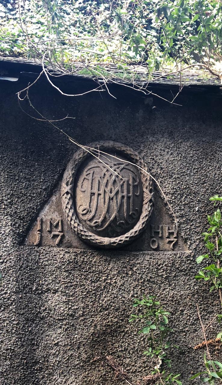 Historic carved crest set within the surrounding stone boundary wall